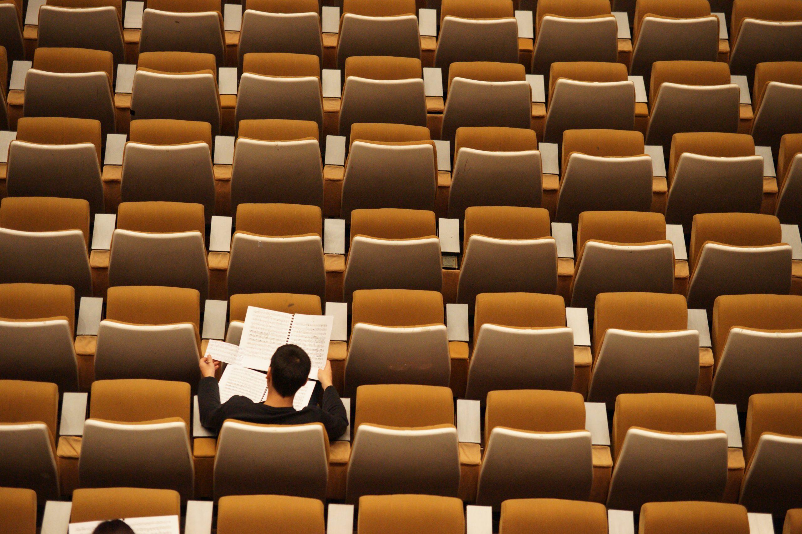 A person sitting in an auditorium by themselves